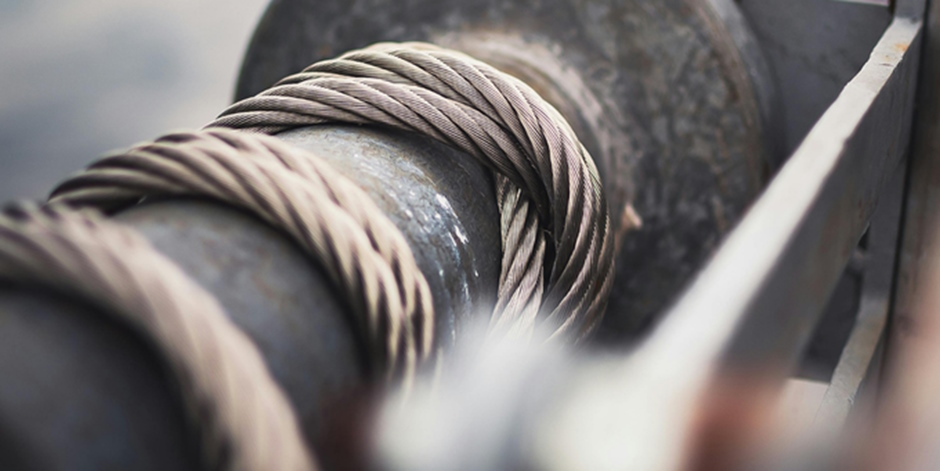 Close-up of a steel cable wrapped tightly around an industrial spool, conveying strength and tension.