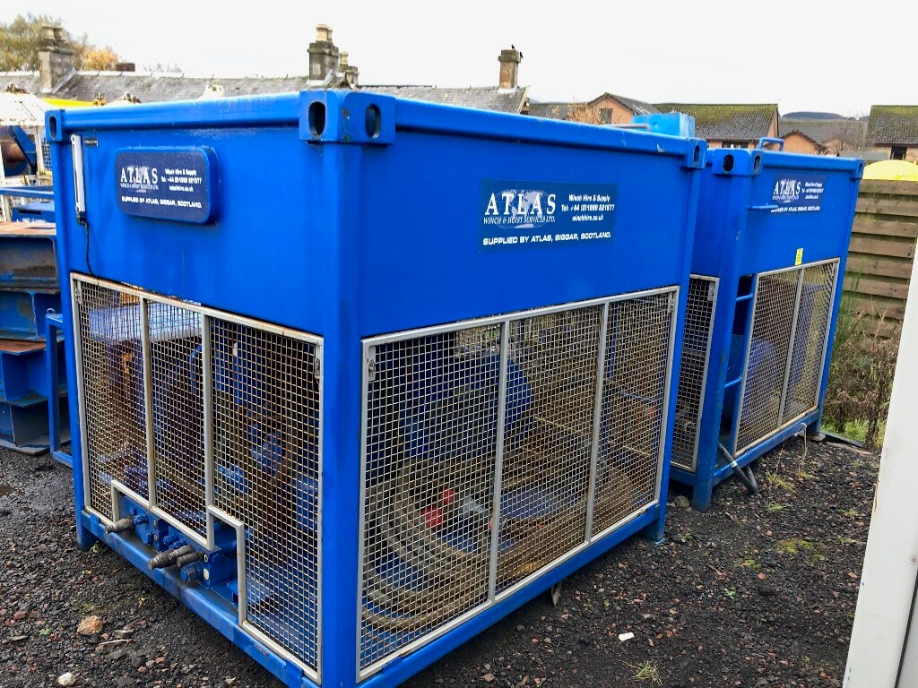 Blue industrial water pump units with mesh panels, labeled "Atlas," are positioned on gravel.
